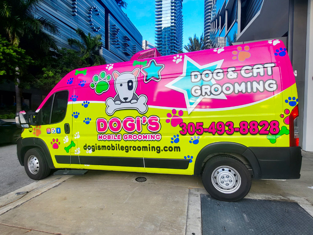 A mobile dog grooming van driving out of a parking garage