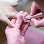 A Skilled Nail Technician Giving A Manicure To A Female Client In A Beauty Salon.