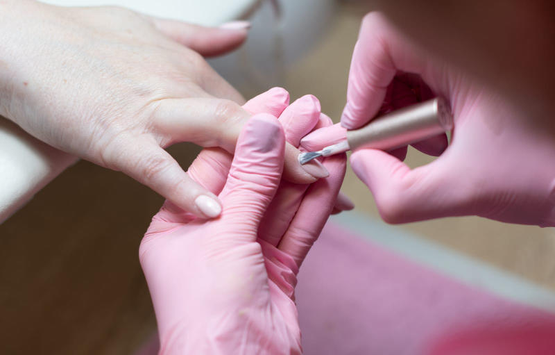 A skilled nail technician giving a manicure to a female client in a beauty salon.