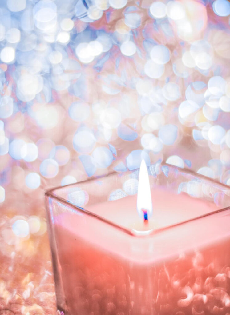 A coral aromatic candle on a glittery background.