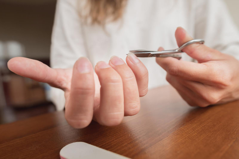 A woman performing a hand care and manicure treatment at home.