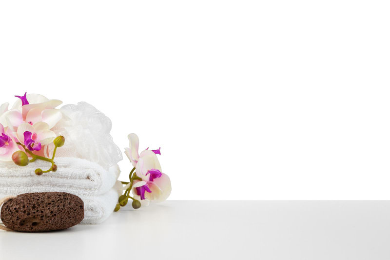 A spa composition with white towels, candles, and flowers isolated on white.