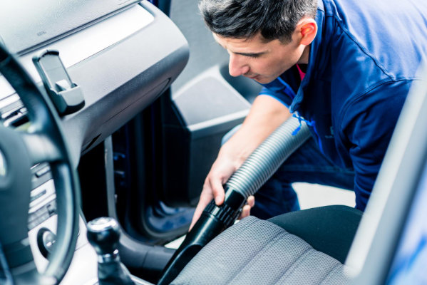 Young man vacuuming the interior of a car