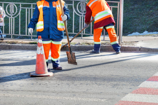 Street cleaners sweeping the road on a sunny day.