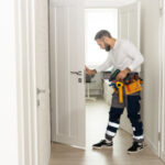 Professional Handyman Working On Fixing A Door Lock At A House Entrance.