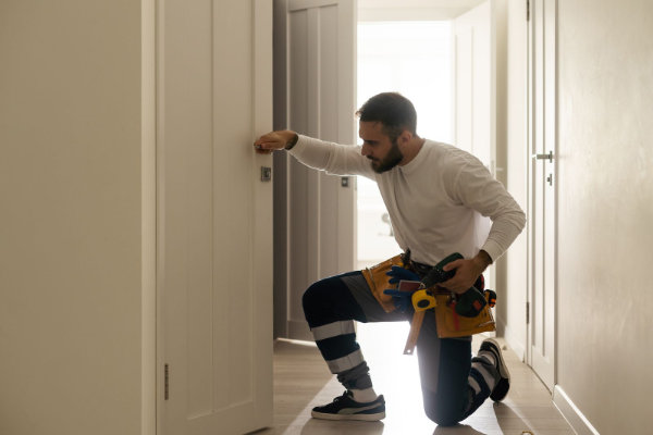 Handyman expertly fixing a door lock at a residential entrance.