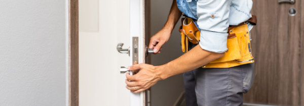 Carpenter's hands expertly installing a lock into a wooden door.