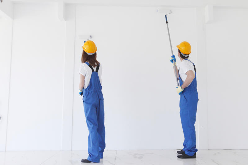 Two workers painting a wall