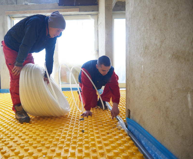 Group of workers installing underfloor heating and cooling in modern home