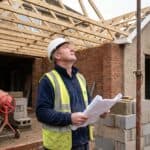Builder checking roof timbers inside the brick shell of a UK rear extension