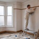 Decorator filling a wall crack above the picture rail in a UK Victorian front room