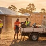Builder and two workers in hi-vis load tools into a white ute at knock-off on a new estate