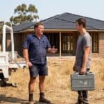 Contractor talks with a younger tradesman holding a toolbox beside a ute on a new house site